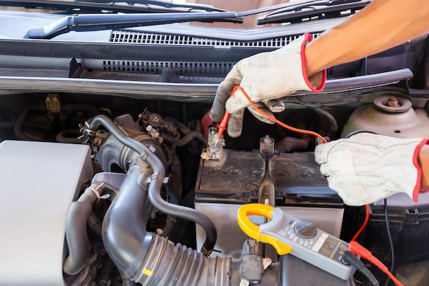 Mecânico de automóveis trabalhando no motor do carro, verificando a bateria no serviço de reparo e manutenção da garagem mecânica