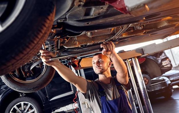 Foto mecânico de automóveis verificando o equipamento de corrida do automóvel na estação de serviço trabalhador masculino consertando problema com o carro conceito de manutenção do veículo