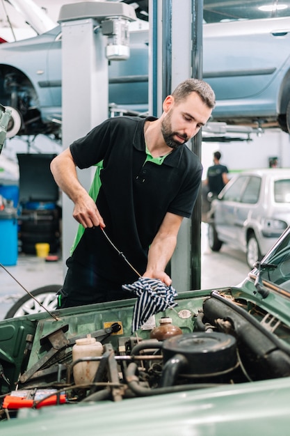 Foto mecânico de automóveis verificando o nível de óleo