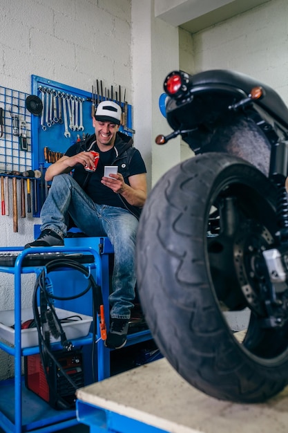 Mecânico de motocicletas descansando tomando uma cerveja