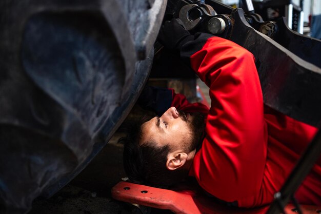 Mecânico deitado debaixo de um tractor a reparar máquinas agrícolas