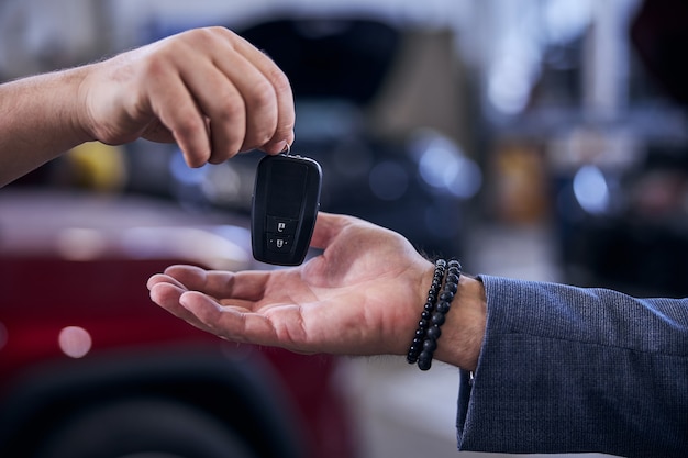 Mecânico entregando a chave do carro eletrônico moderno ao homem