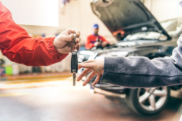 Mecánico entregando llaves de automóvil de mujer