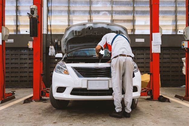 El mecánico está comprobando el coche en el centro de servicio de reparación de automóviles