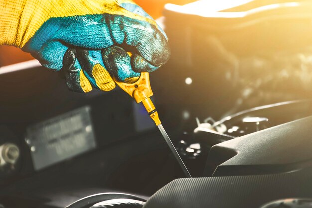 El mecánico está tirando del medidor de nivel de aceite del motor del coche para comprobar el nivel de aceite