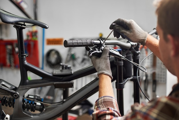 Foto mecânico fazendo serviço em oficina de bicicletas usando ferramentas