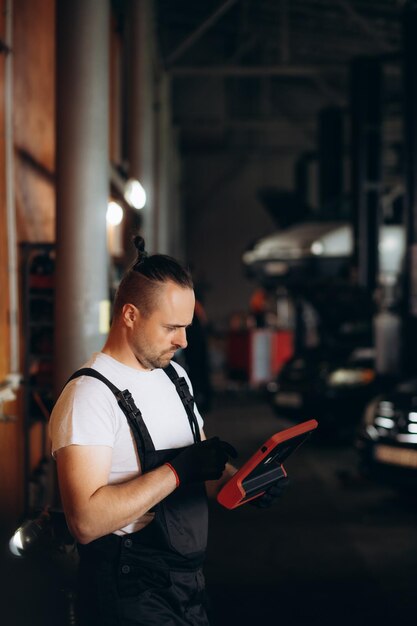 Mecánico feliz usando una tableta digital en un taller de reparación de automóviles