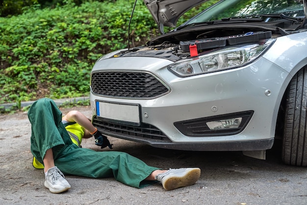 Mecânico feminino de uniforme tentando reparar o automóvel que quebrou