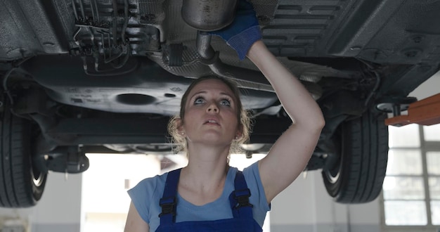 Foto mecânico feminino trabalhando debaixo de um carro