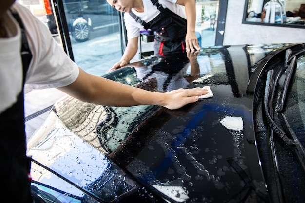 Mecánico con film transparente, protección de pintura de coche. El mecánico instala una película protectora para la pintura del automóvil. Instale una película protectora para la pintura del automóvil. Concepto de envoltura de coche.