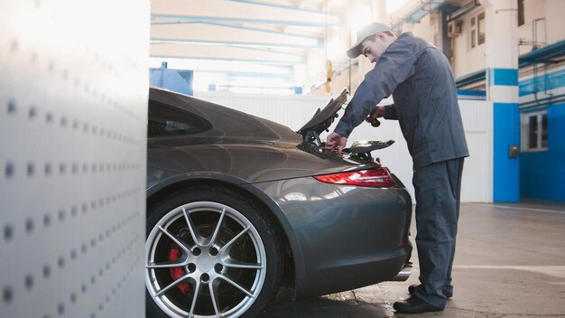 Mecánico en garaje de automóviles control de capó para el coche de lujo