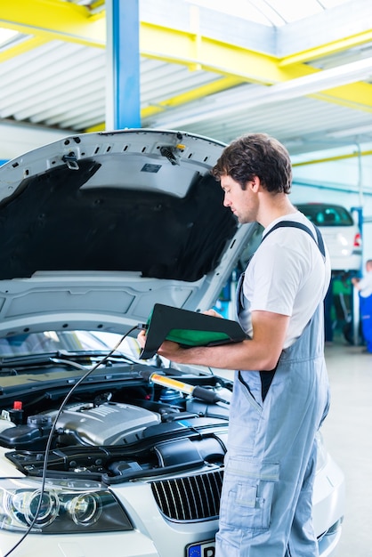 Foto mecánico con herramienta de diagnóstico en taller de automóviles