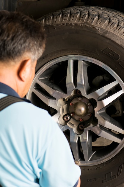 Mecánico Holding Car Tire en el garaje