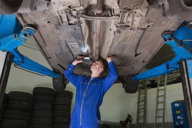 Mecânico inspecionando carro usando lanterna