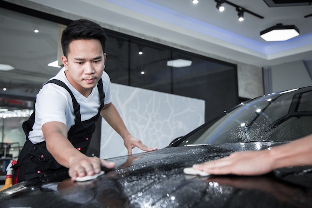 Mecânico instala filme de proteção de pintura de carro.