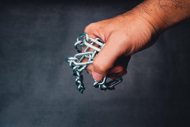 El mecánico lleva una cadena de metal en la mano con un fondo de color negro