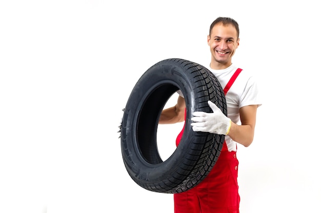 Mecánico llevando un neumático sobre un fondo blanco.