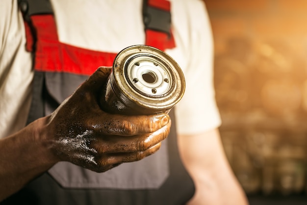 Mecánico. Manos sucias sosteniendo el filtro de aceite.