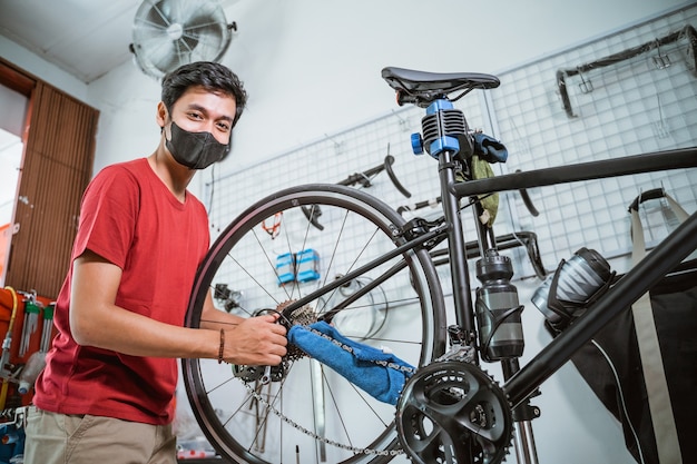 Un mecánico en máscara trabajando aprieta el eje de la bicicleta con una llave