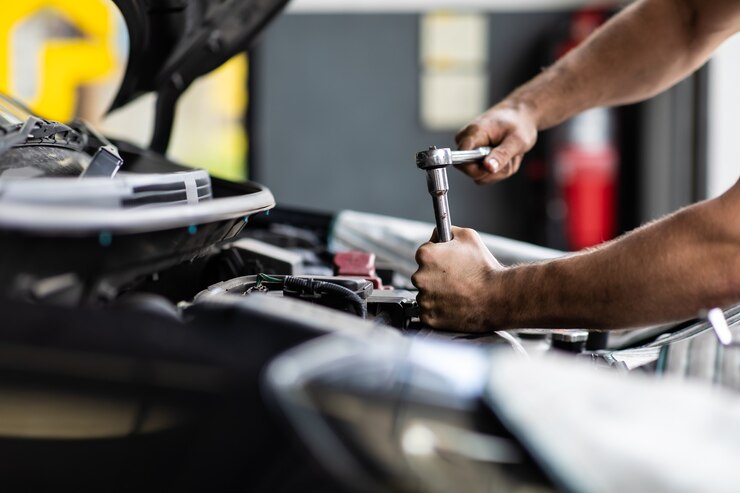 Mecánico masculino caucásico repara el coche en el garaje. Concepto de garaje de mantenimiento y servicio automático de automóviles. Mano y llave del primer.