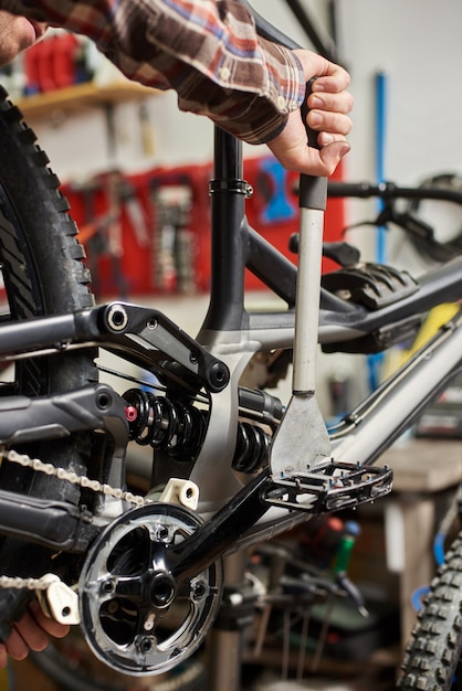 Mecânico masculino fazendo serviço em oficina de bicicletas usando ferramentas