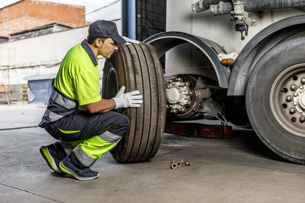 Mecánico masculino reparando y arreglando la rueda del coche en el garaje