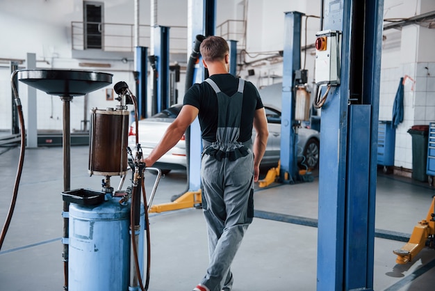 Mecánico masculino utiliza un dispositivo especial para reparar automóviles rotos en el garaje