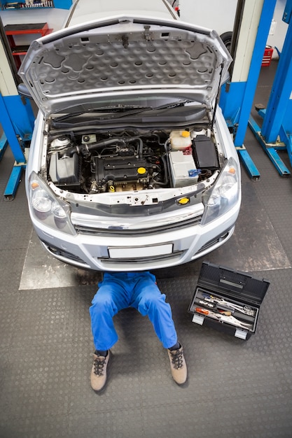 Mecánico mintiendo y trabajando bajo el auto