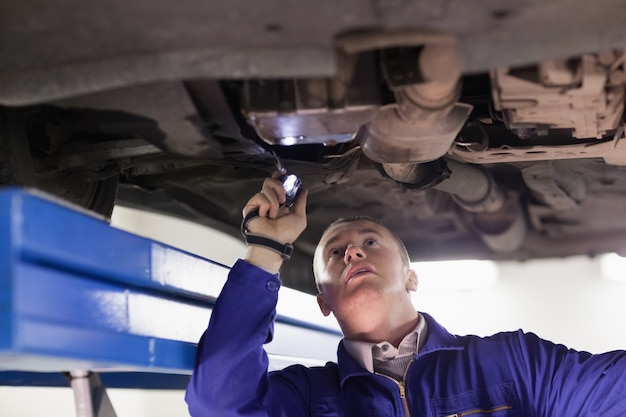 Foto mecánico mirando un automóvil mientras sostiene una linterna