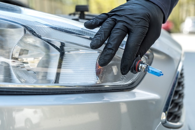 Mecânico mudando a nova lâmpada de halogênio no farol do carro. indústria automobilística