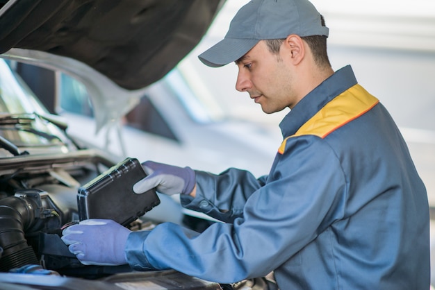 Mecânico mudando o óleo de um motor de carro, manutenção e conceito de manutenção