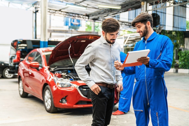 El mecánico muestra la lista de verificación del automóvil para el cliente con desenfoque de su asistente de verificación del automóvil rojo