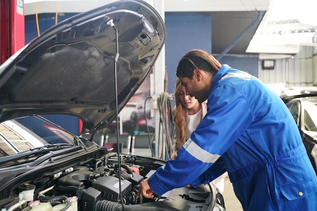 Mecánico en overol azul que verifica la capacidad de servicio del motor del automóvil