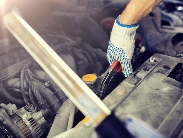 Foto mecánico con pinzas reparando un coche en el taller