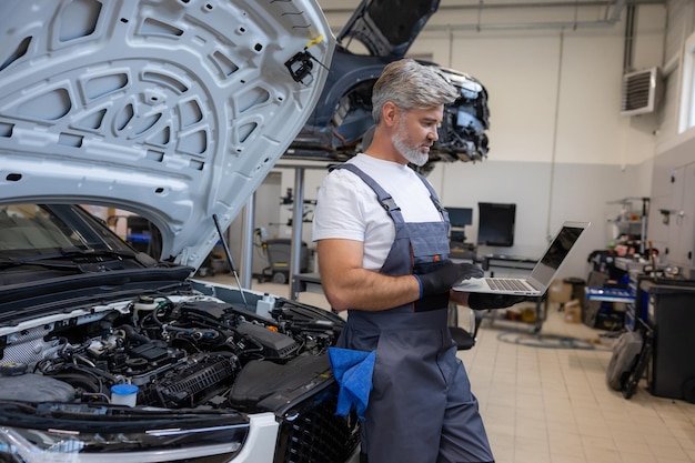 Mecánico con portátil en un taller de reparación de automóviles