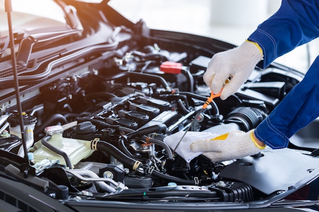 Foto mecánico profesional en uniforme. verifique la calidad del aceite de motor nuevo antes de entregarlo a los clientes. mientras trabajaba en el centro de reparación de automóviles.