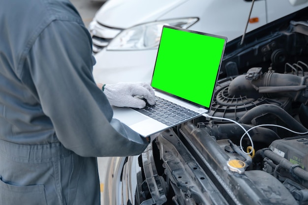 Foto mecânico qualificado usando um computador portátil para verificar coletar informações durante o trabalho um motor de carro