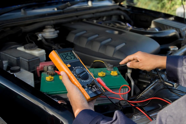 Mecánico que comprueba el voltaje de la batería del coche