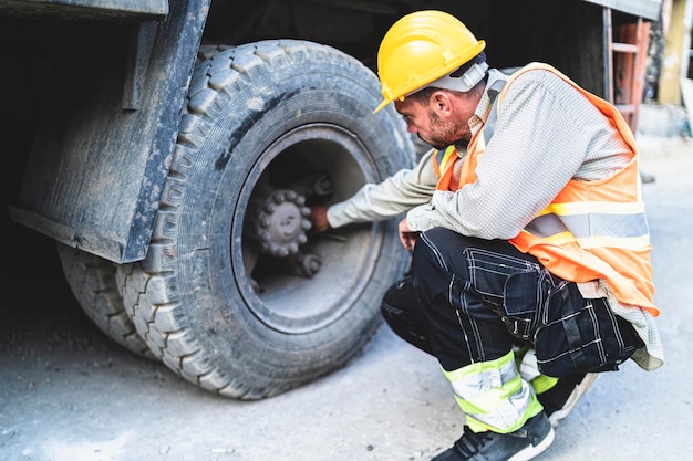 Foto mecánico que examina el neumático de un camión
