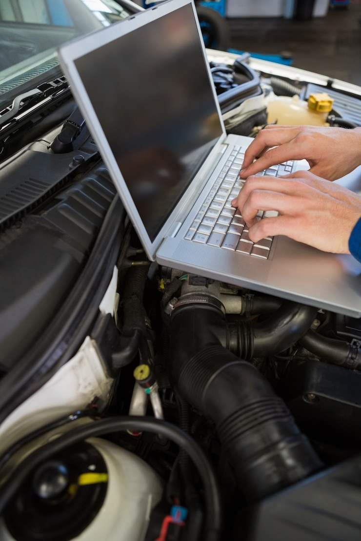 Foto mecánico que usa la computadora portátil en el coche