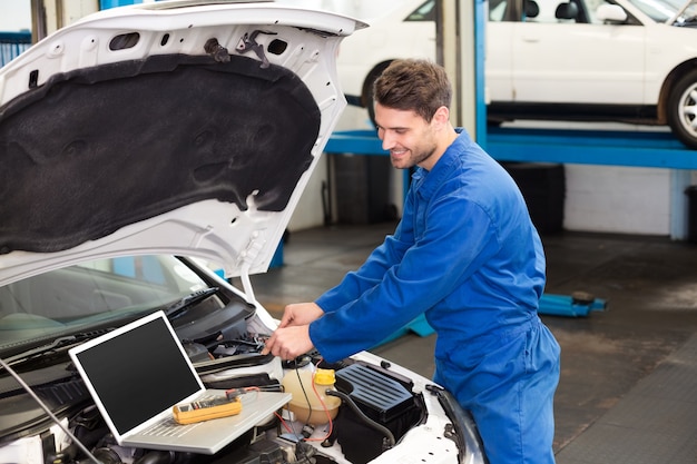 Mecánico que usa la computadora portátil en el coche