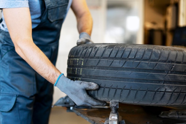 Mecánico reemplazando un neumático de coche usado en un taller