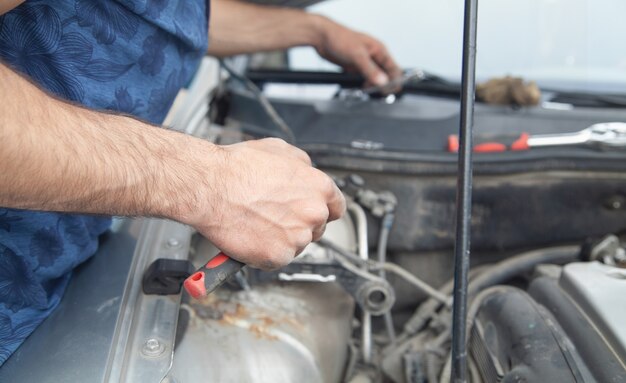 El mecánico repara el motor del coche. Mantenimiento del auto