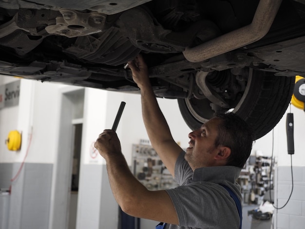 Foto mecânico reparando carro na garagem.