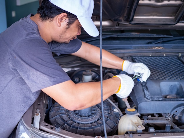 Mecânico segurando uma alça de chave de bloco enquanto conserta um carro.