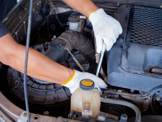 Mecânico segurando uma alça de chave de bloco enquanto conserta um carro.