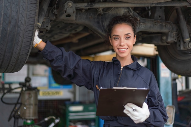 Mecánico de sexo femenino sonriente y trabajo de reparación de mantenimiento de un coche en el garaje de servicio automático