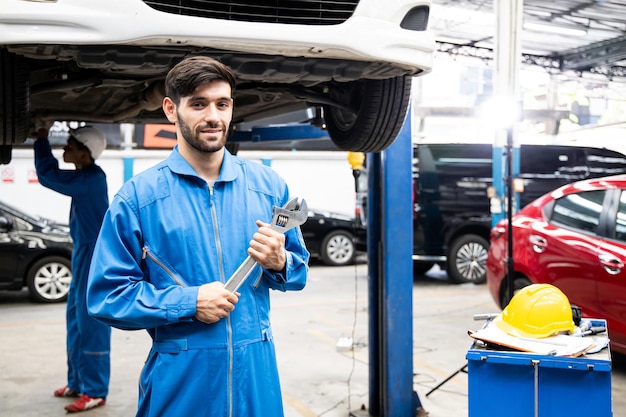 Mecánico sonriente guapo confiado en uniforme. Mecánico de automóviles que trabaja en el centro de servicio automotriz.