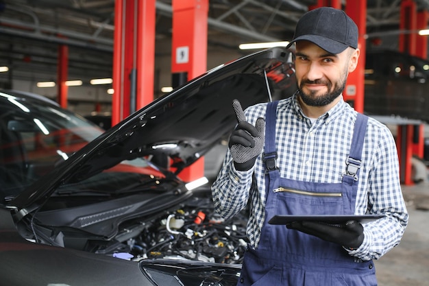 Mecánico sonriente usando una tableta en el garaje de reparación