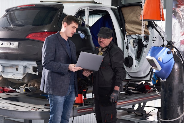 Foto mecánico y técnico automotriz trabajando en taller de reparación.